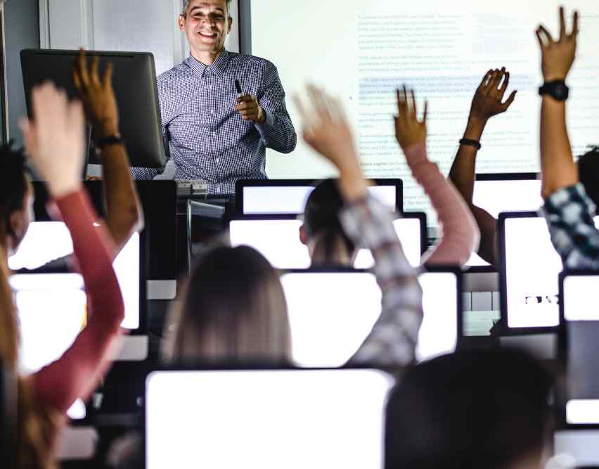 Enthusiastic engagement in an English class with all students' hands raised, indicating active participation