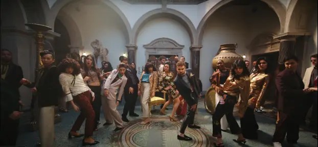 A still image from Ed Sheeran's 'Azizam' music video showing a group of people frozen mid-dance at a party, used as a visual prompt for an ESL prediction activity.
